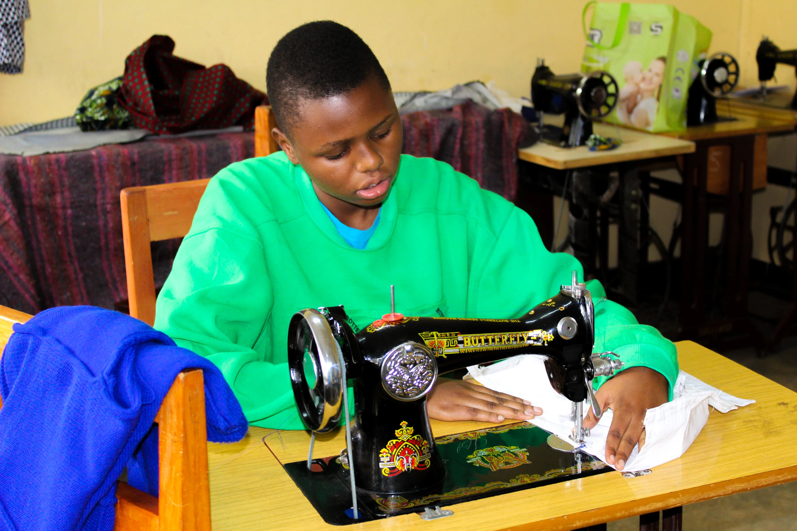 A tailor working with a sewing machine, representing the Tailoring trade